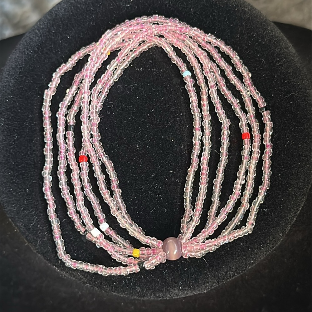 6 strand pink seed bead bracelet. Big purple bead keeps is gathered.